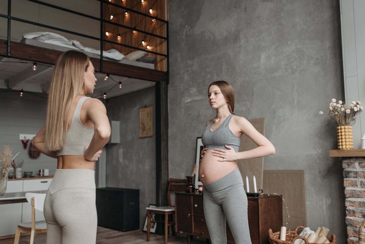 Expectant mother practicing prenatal yoga with guidance in a cozy home setting.